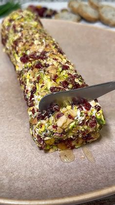 a knife is on top of a cracker covered in nuts and cranberries