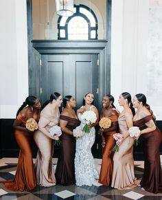 a group of women standing next to each other in front of a door holding bouquets