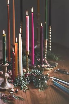 a bunch of lit candles sitting on top of a wooden table next to other items