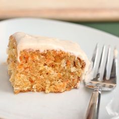 a piece of carrot cake with icing on a white plate next to a fork