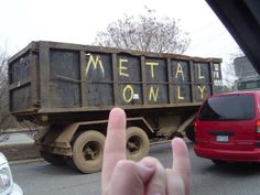 a person's hand is in front of a dump truck with the word metal on it