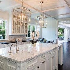 a large kitchen with an island and chandelier hanging from it's ceiling