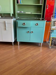 three different colored cabinets sitting on top of a hard wood floor next to each other