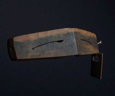 a piece of wood with a knife sticking out of it's back end, against a dark background