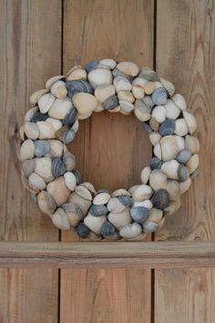 a wreath made out of seashells sitting on top of a wooden wall