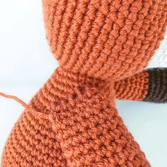 an orange knitted neck tie on a white tablecloth with a black and brown crochet pattern