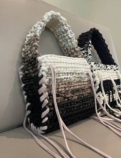 three woven purses sitting on top of a white table next to each other with tassels hanging from them