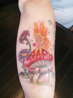 a tattoo on the leg of a woman with flowers and a fairy sitting on top of a mushroom