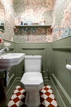 a toilet and sink in a small room with green walls, checkered flooring