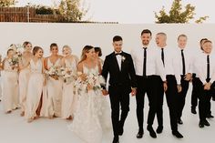 a group of people standing next to each other in front of a white wall with flowers