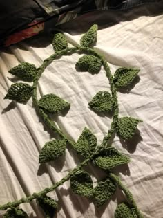 a crocheted green plant is laying on a white sheet with the leaves still attached to it