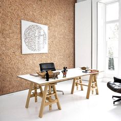 an office with corked walls and leather chairs in front of the desk is shown