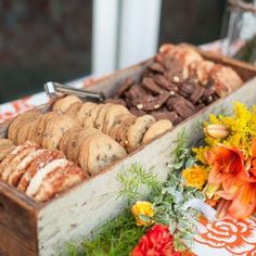 a wooden box filled with lots of different types of cookies and pastries on top of a table