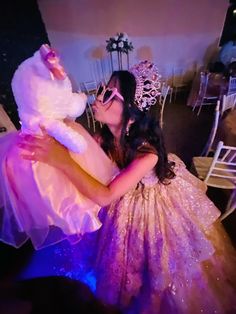 a woman in a purple dress is kissing a white teddy bear on her chest at a party