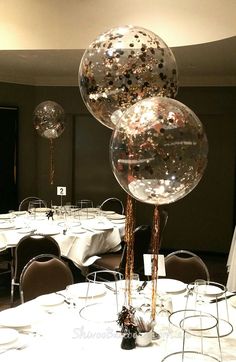 three large clear balloons are on top of the tables at a wedding reception with white tablecloths