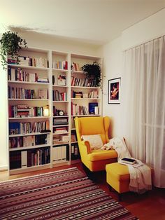 a yellow chair sitting in front of a book shelf filled with books