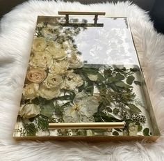 a white furnishing with flowers on it and a gold frame holding a mirror