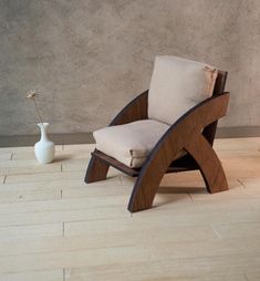 a wooden chair sitting on top of a hard wood floor next to a white vase