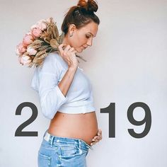 a pregnant woman with flowers on her head and the number twenty nine behind her belly