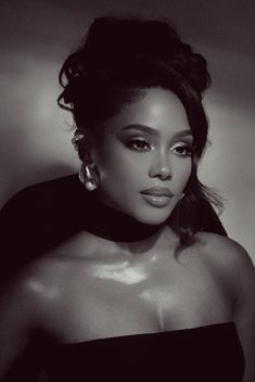 a black and white photo of a woman in a strapless dress with large earrings