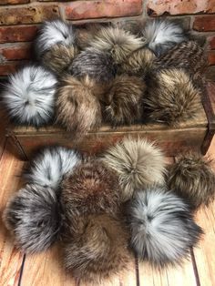 several different colored fur balls sitting on top of a wooden box next to a brick wall