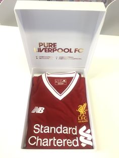 a red shirt in a white box with the liverpool logo on it's chest