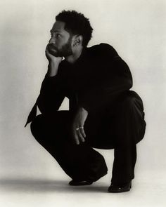 a black and white photo of a man with his hand on his chin, leaning forward