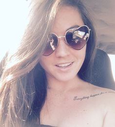 a woman with sunglasses on her head and tattoos on her chest is sitting in the back seat of a car