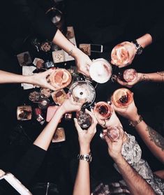 a group of people holding wine glasses in the middle of a table