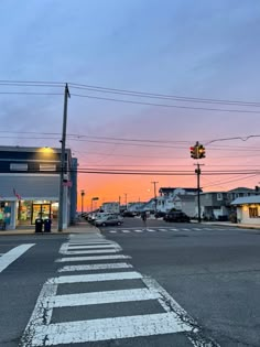 an intersection with cars and buildings in the background at sunset or dawn, as seen from across the street