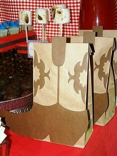 some brown paper bags sitting on top of a table with cupcakes in them