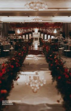 a long table with red flowers on it and chandelier hanging from the ceiling