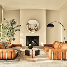 a living room with two couches and a mirror on the wall over a fireplace