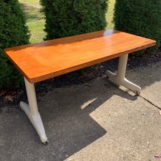 a wooden table sitting in front of some bushes