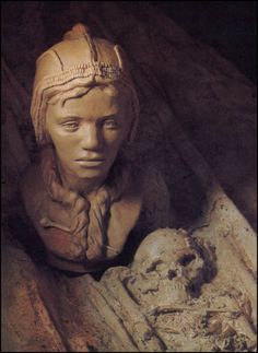 a statue of a woman with a skull in her lap and wearing a headdress