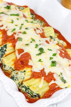 a casserole dish with spinach, cheese and sauce in it on a white plate