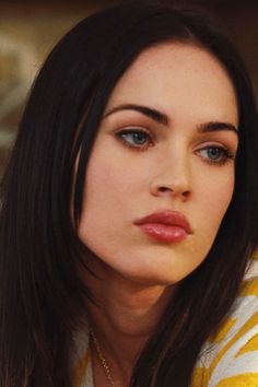 a close up of a person wearing a yellow and white shirt with a cell phone in her hand