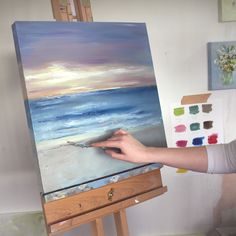 a woman is painting on an easel in her studio