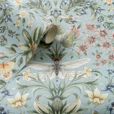 a blue floral wallpaper with a dragonfly on it's back and wings