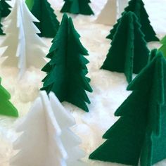 green and white christmas trees are sitting on the snow covered ground, ready to be made into decorations