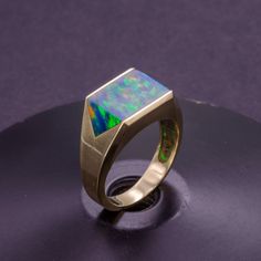 Make a statement with this stunning solid gold signet ring, featuring a large lab-made black opal inlay that shimmers with a captivating iridescence. The inlay is expertly crafted and set into the gold with precision, resulting in a bold and unique design that's sure to turn heads. Unlike cheap hollow or plated rings, this signet ring is crafted from solid gold throughout for a luxurious and high-quality finish that's built to last. Perfect for men who appreciate fine jewelry and bold design, th Formal Opal Ring With Polished Finish, Modern 14k Gold Opal Ring With Polished Finish, Modern Opal Ring In 14k Gold With Polished Finish, Modern Formal Opal Jewelry, Customization Ideas, Jewellery Boutique, Black Opal Ring, Fashionable Accessories, Opal Band