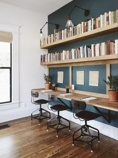 two desks with chairs and bookshelves in front of them on the wall