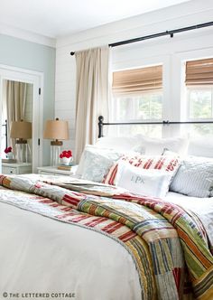 a bed with white sheets and pillows in a bedroom next to two lamps on either side of the bed