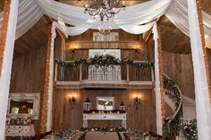 the inside of a barn decorated with white draping and christmas lights on the ceiling