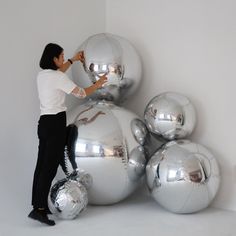 a man standing in front of some shiny silver balls and looking at something on the wall