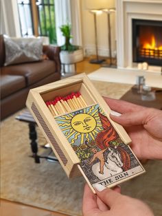 a person holding a match box in front of a fire place with the sun on it