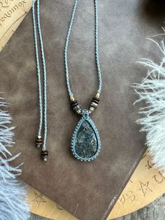 two necklaces on top of a table next to a book and feathery material