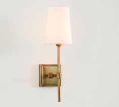 a wall light with a white shade on it's side and a gold finish