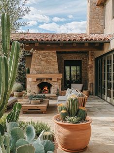 an outdoor living area with cactus, couch and fire place in the middle of it