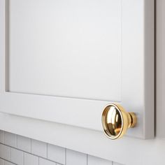 a close up of a gold door handle on a white cabinet